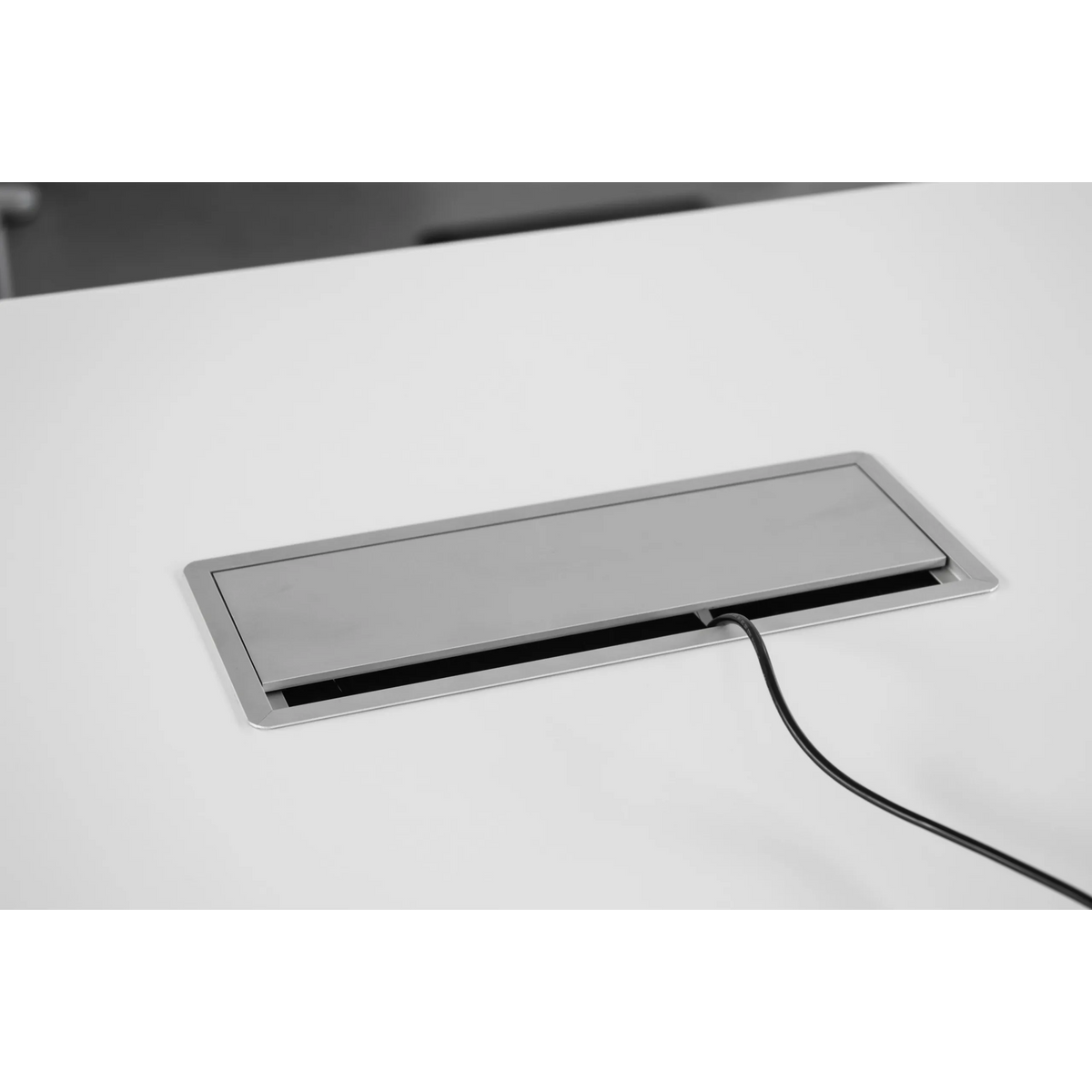 Silberne Kabelklappe des Zubehörs ELKL 30 mit herausgeführtem Kabel auf einer weißen Tischplatte von hjh OFFICE PRO