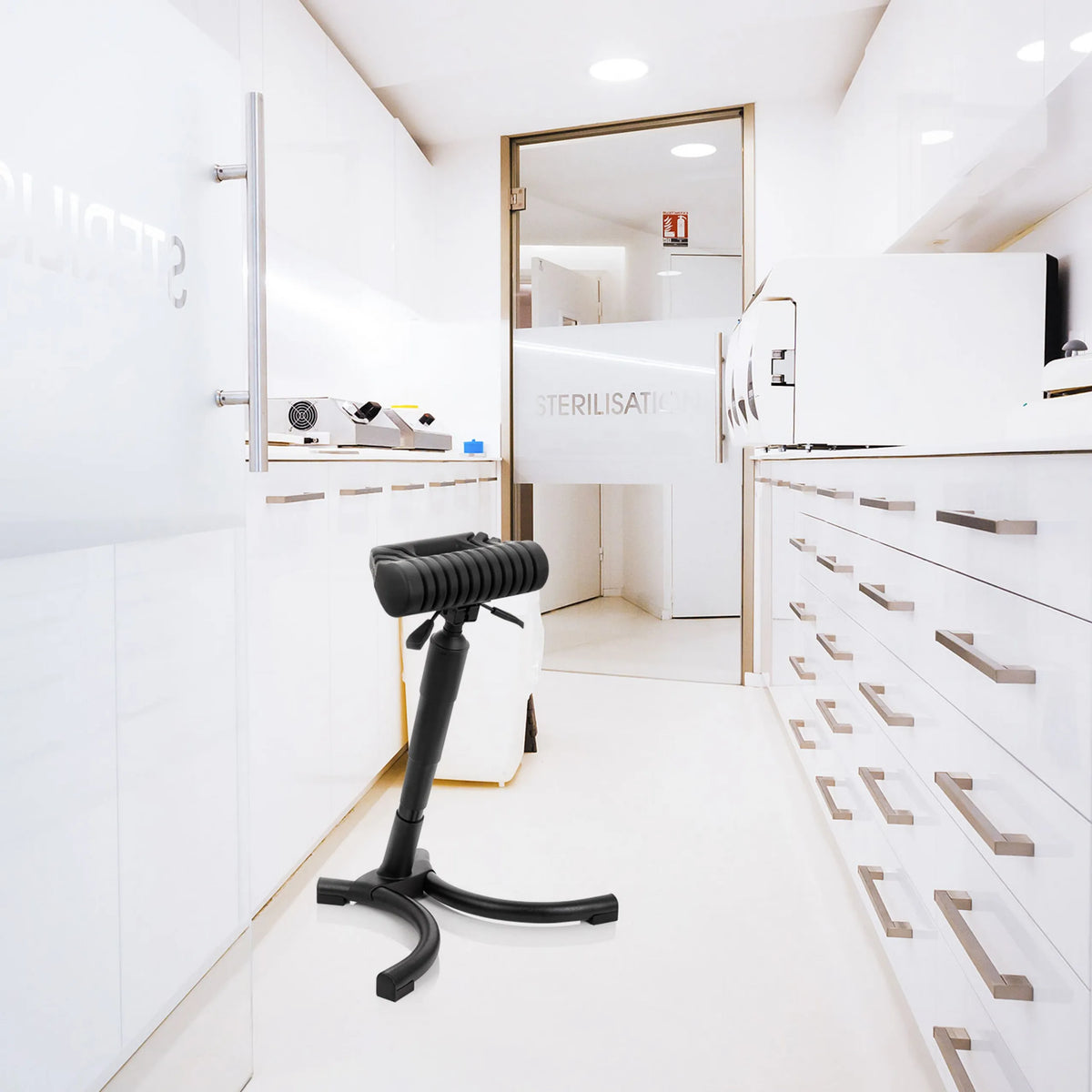 Schwarze Stehhilfe TOP WORK 33 mit gepolsterter Sitzfläche und Sternfuß in einer hellen Sterilisationsumgebung von hjh OFFICE