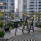 Schwarzer Klapptisch TRAVANO T1 mit Maßen 79 × 79 cm auf einem Balkon von hjh LIVING (KI-generiertes Bild)